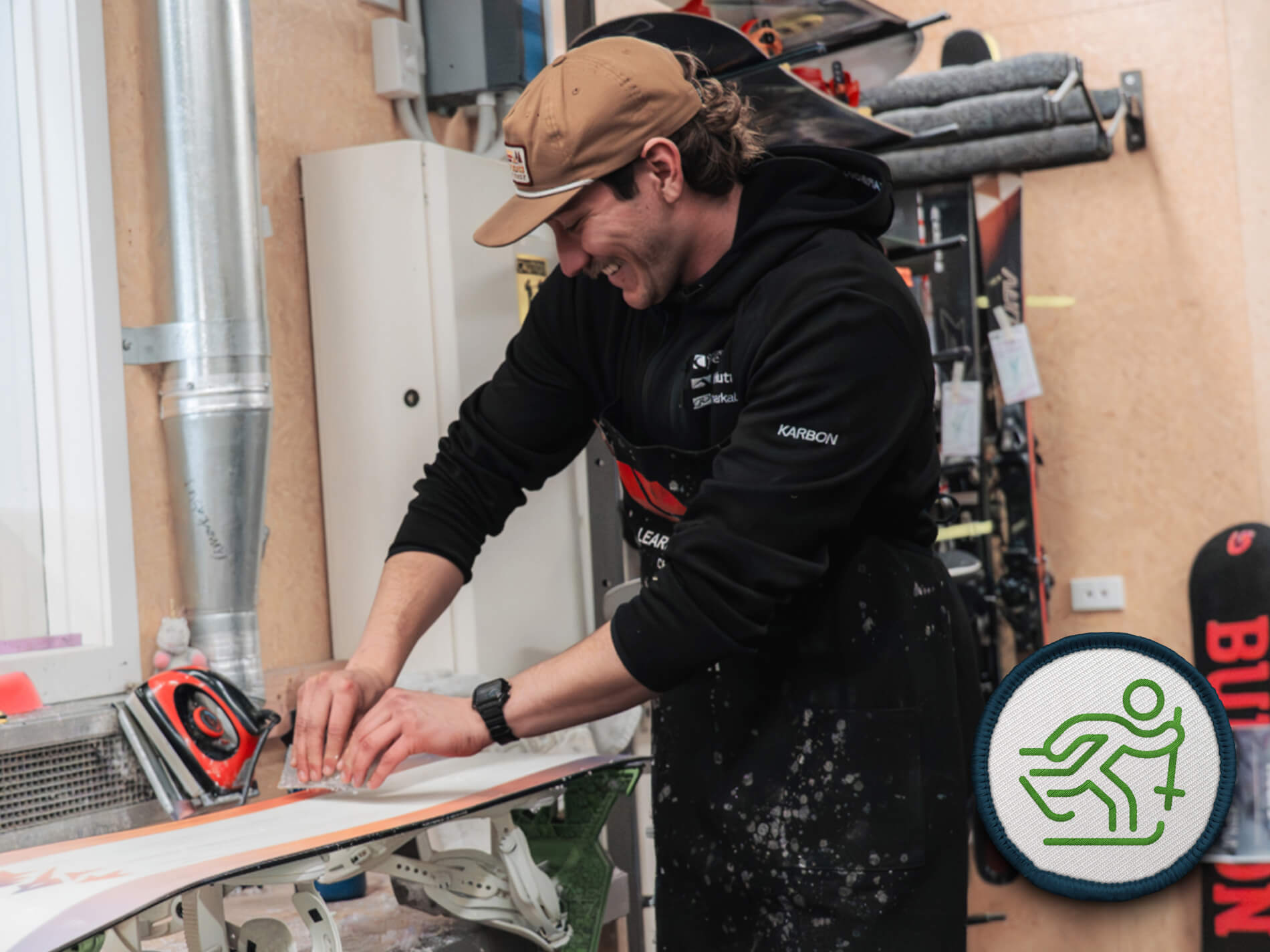 Man tuning a pair of skis in Remarkables ski workshop filled with ski equipment and tools.